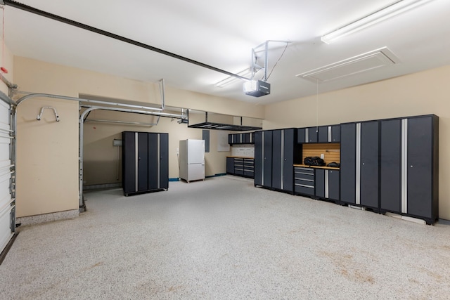 garage with a garage door opener and white refrigerator