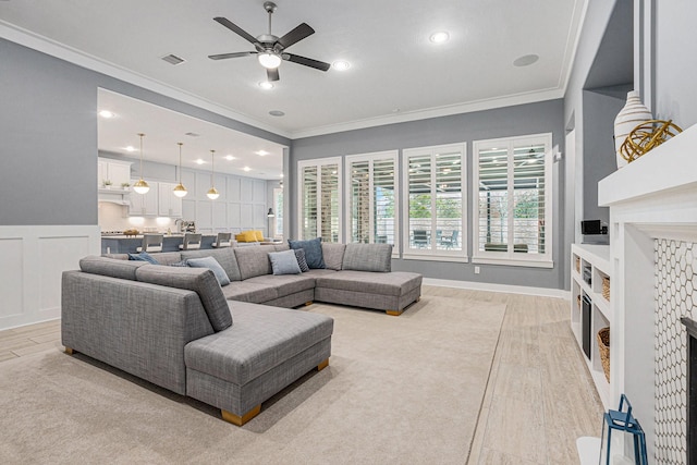 living room featuring light wood-type flooring, crown molding, and ceiling fan