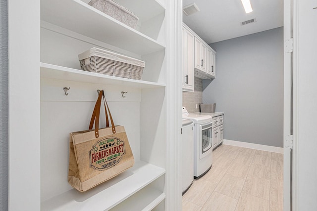 laundry area with washing machine and clothes dryer and cabinets