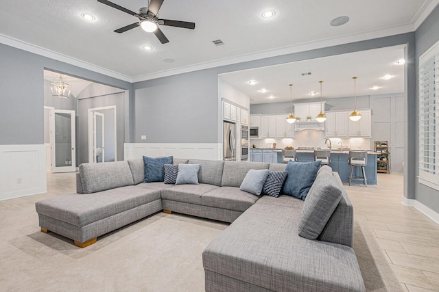 living room with ceiling fan with notable chandelier and ornamental molding