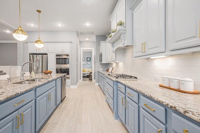 kitchen with hanging light fixtures, blue cabinetry, stainless steel appliances, white cabinets, and sink