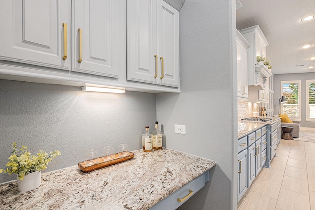 kitchen with light tile patterned flooring, white cabinetry, light stone countertops, and high end stainless steel range oven