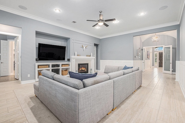 living room with ceiling fan with notable chandelier and ornamental molding