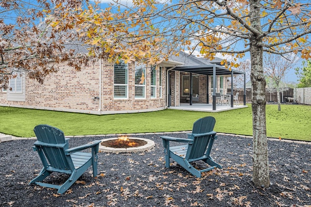 rear view of property with a yard, a patio, and a fire pit