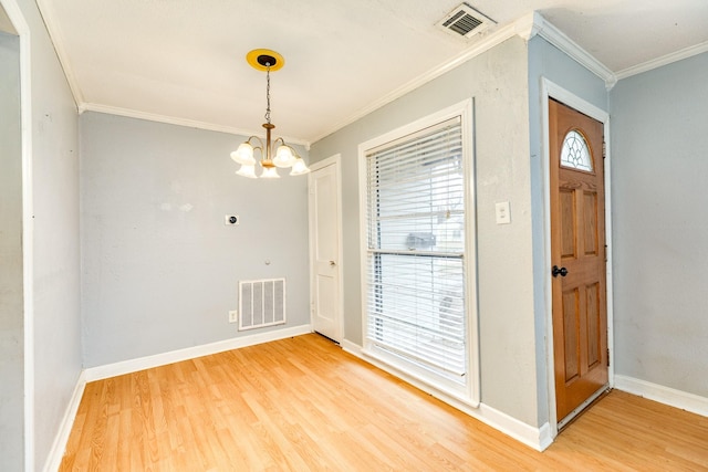 foyer entrance featuring hardwood / wood-style flooring, ornamental molding, an inviting chandelier, and a wealth of natural light