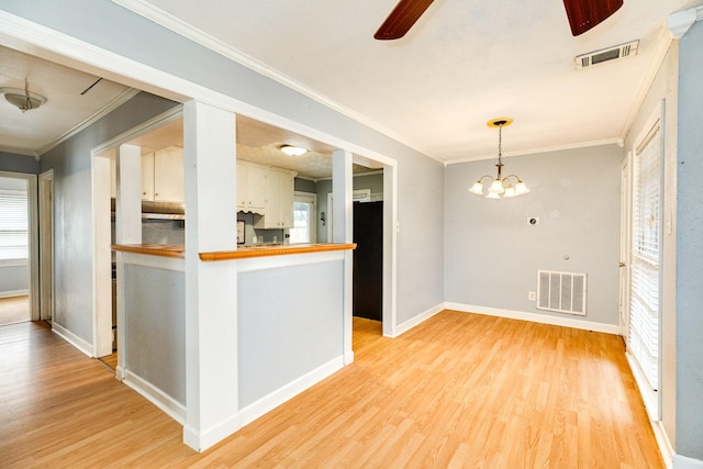 kitchen with butcher block countertops, light hardwood / wood-style flooring, white cabinetry, ornamental molding, and decorative light fixtures