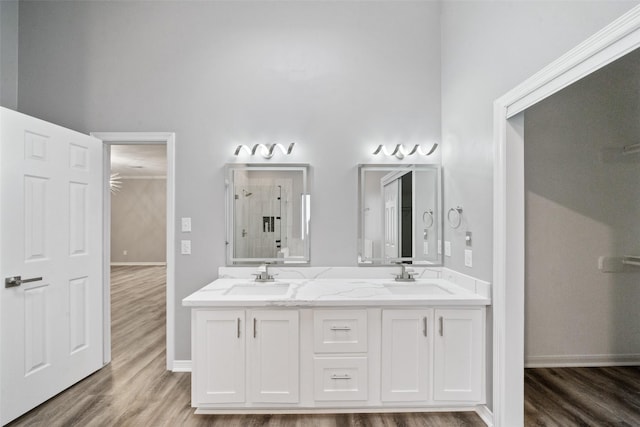 bathroom with walk in shower, wood-type flooring, vanity, and a high ceiling