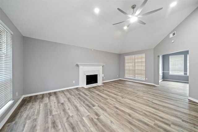 unfurnished living room with ceiling fan, lofted ceiling, a premium fireplace, and light hardwood / wood-style flooring