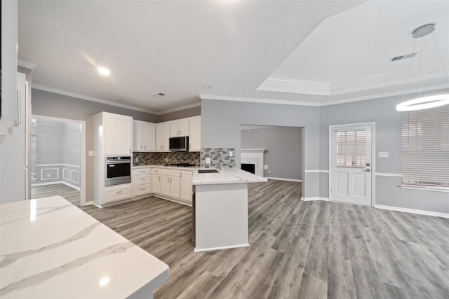 kitchen featuring pendant lighting, tasteful backsplash, white cabinets, kitchen peninsula, and stainless steel appliances