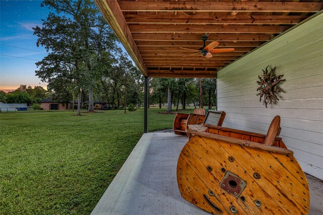 yard at dusk featuring a patio area and ceiling fan