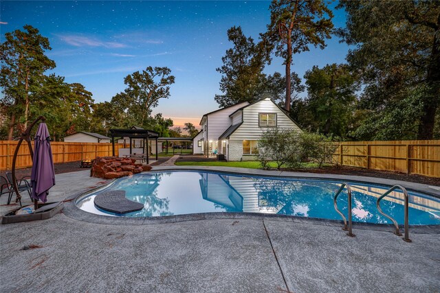 pool at dusk featuring a patio