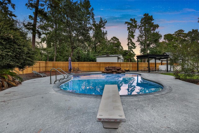 pool at dusk with a diving board and a patio area