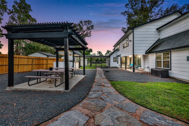 yard at dusk featuring a pergola and a patio area