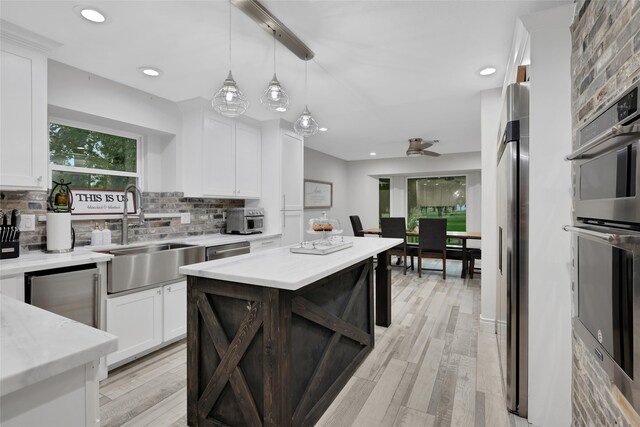 kitchen featuring pendant lighting, white cabinetry, sink, a center island, and stainless steel appliances