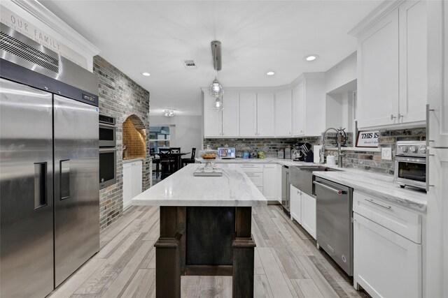 kitchen featuring pendant lighting, white cabinetry, stainless steel appliances, and a kitchen island