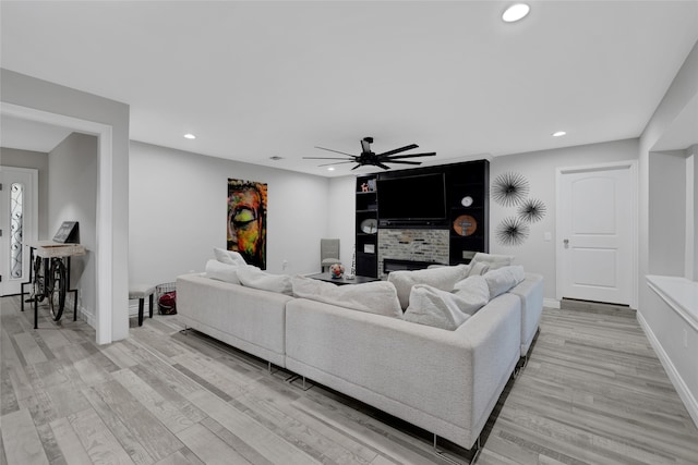 living room with ceiling fan, light hardwood / wood-style floors, and a brick fireplace