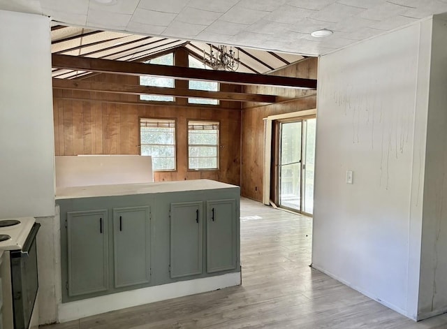 kitchen featuring lofted ceiling, wooden walls, light hardwood / wood-style floors, and stove