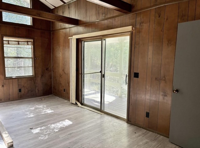 interior space featuring light hardwood / wood-style floors, vaulted ceiling, and wood walls