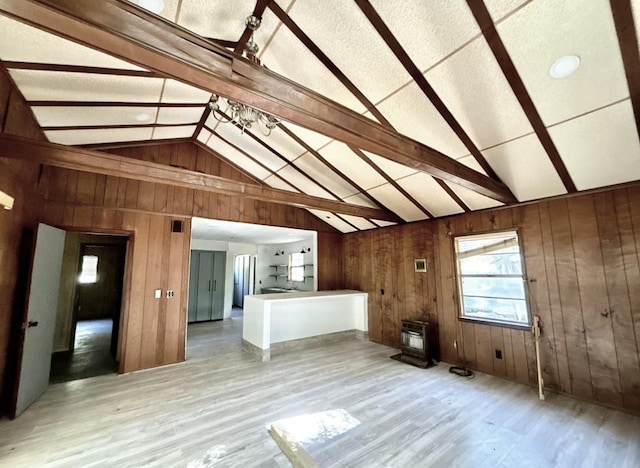 additional living space with lofted ceiling with beams, heating unit, wooden walls, and light hardwood / wood-style floors