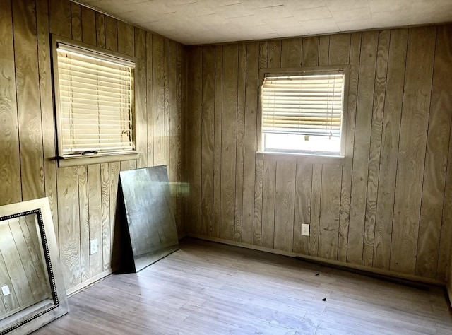 unfurnished room featuring wood walls, a fireplace, and light wood-type flooring