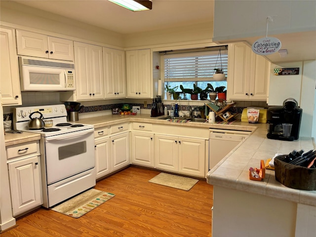 kitchen with sink, tile counters, white appliances, light hardwood / wood-style floors, and white cabinets