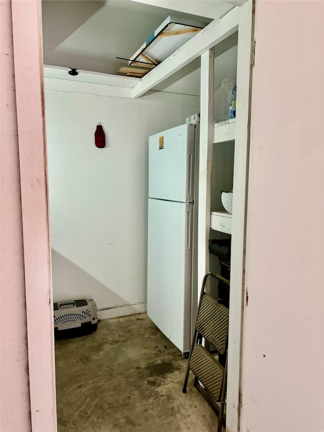 interior space featuring concrete flooring and white fridge