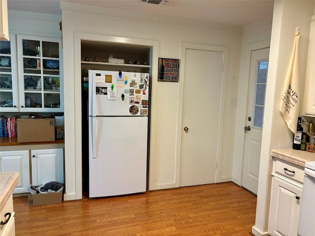 kitchen featuring white cabinetry, light hardwood / wood-style floors, and white refrigerator