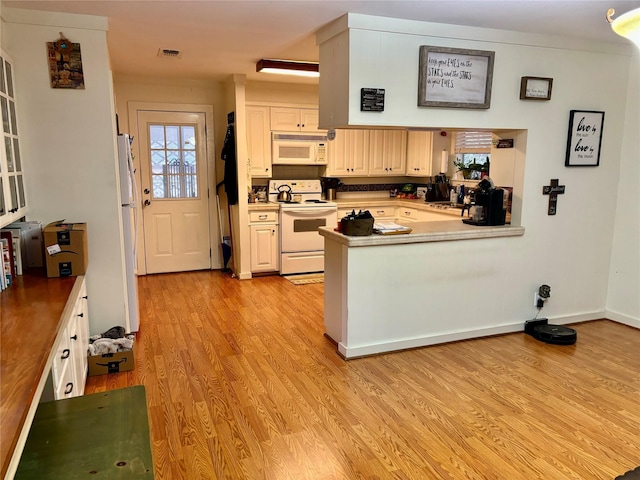 kitchen with sink, white appliances, light hardwood / wood-style flooring, white cabinetry, and kitchen peninsula