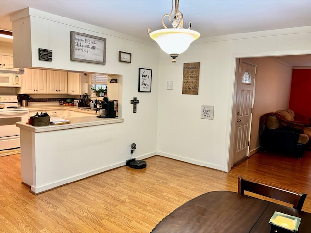 kitchen with light hardwood / wood-style flooring, white appliances, and decorative light fixtures