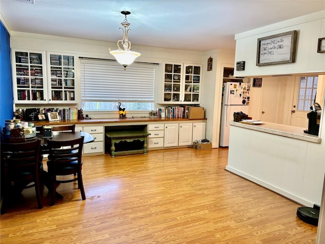 kitchen with white cabinetry, decorative light fixtures, light hardwood / wood-style flooring, and white refrigerator