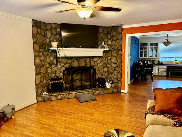 living room featuring a fireplace, wood-type flooring, and ceiling fan