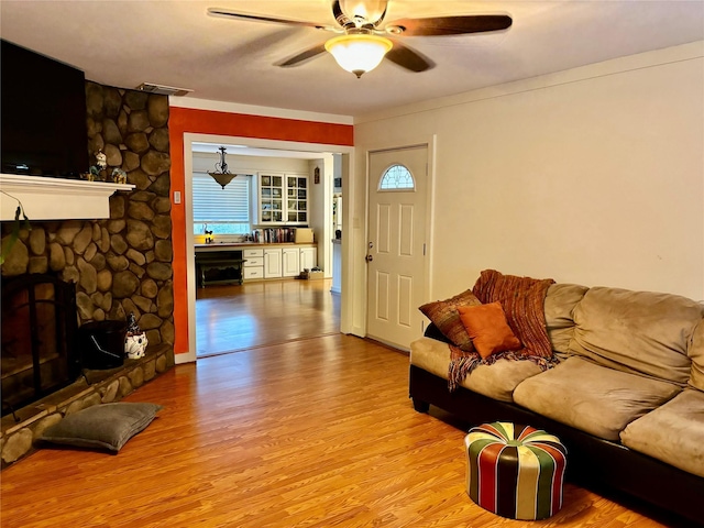 living room with a fireplace, light hardwood / wood-style floors, ceiling fan, and plenty of natural light