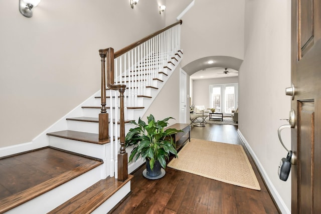 entryway with dark hardwood / wood-style flooring, a towering ceiling, and ceiling fan