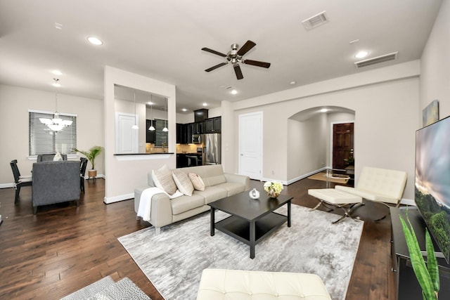 living room with dark wood-type flooring and ceiling fan with notable chandelier