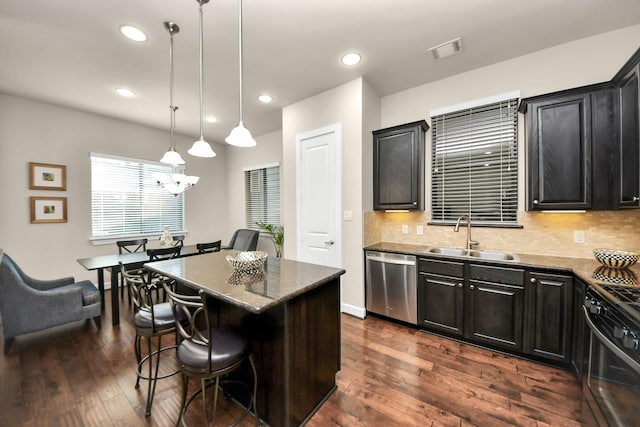 kitchen featuring a breakfast bar, gas stove, decorative light fixtures, a center island, and stainless steel dishwasher