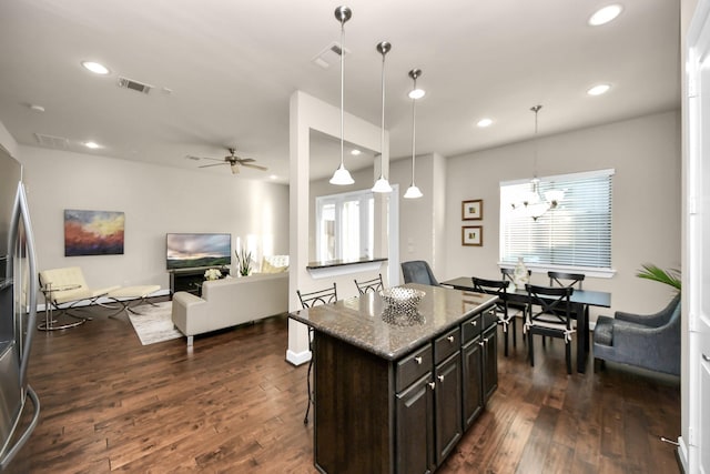 kitchen with a kitchen island, dark hardwood / wood-style floors, decorative light fixtures, a kitchen breakfast bar, and dark brown cabinets