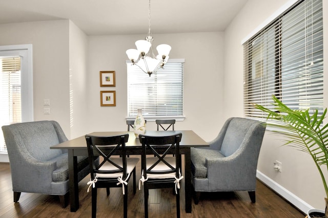 dining space featuring dark wood-type flooring and an inviting chandelier