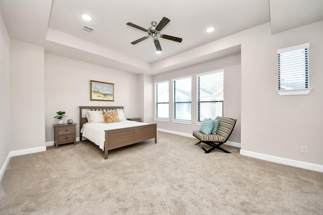 bedroom featuring a tray ceiling, light colored carpet, and ceiling fan