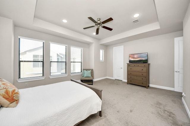 bedroom with a tray ceiling, light colored carpet, and ceiling fan