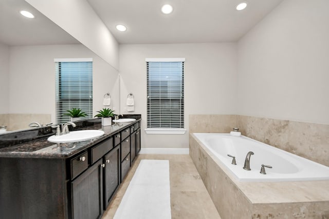 bathroom with tile patterned flooring, vanity, and a relaxing tiled tub