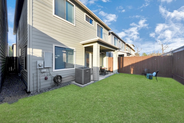 rear view of house with central AC unit and a lawn