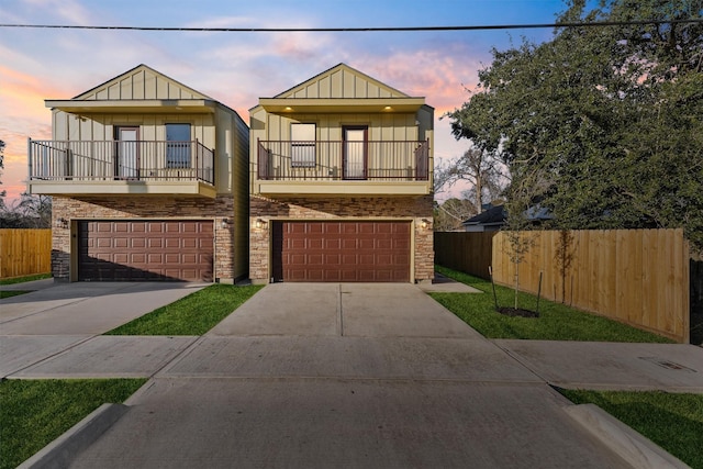 view of front of home with a garage, concrete driveway, a balcony, fence, and board and batten siding