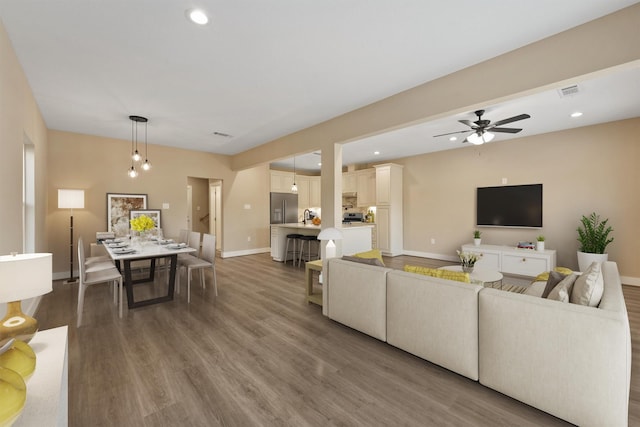 living room with recessed lighting, visible vents, baseboards, and wood finished floors