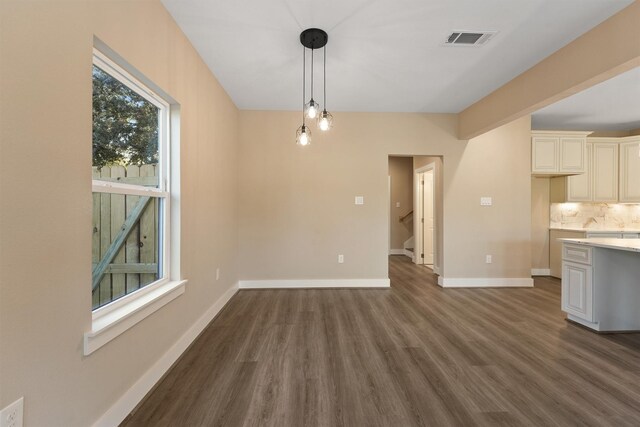 interior space with dark wood-type flooring, pendant lighting, cream cabinetry, and decorative backsplash