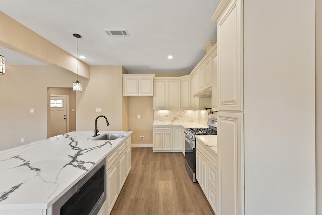 kitchen featuring light stone counters, stainless steel appliances, tasteful backsplash, visible vents, and a sink