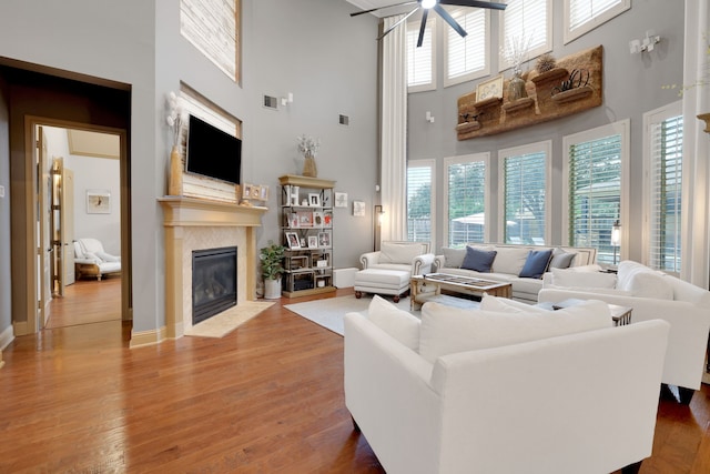 living room featuring a fireplace with flush hearth, a high ceiling, wood finished floors, and a wealth of natural light