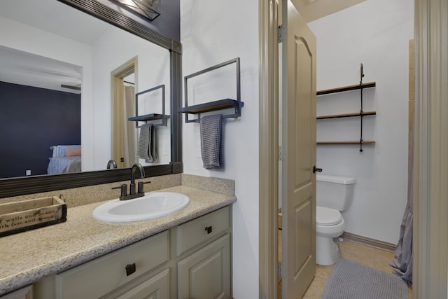 ensuite bathroom featuring baseboards, toilet, ensuite bathroom, tile patterned flooring, and vanity