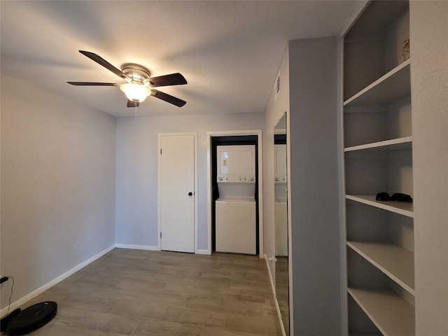 interior space featuring stacked washer and dryer, a textured ceiling, and light hardwood / wood-style floors