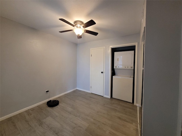 unfurnished room with ceiling fan, stacked washer and clothes dryer, and light hardwood / wood-style floors