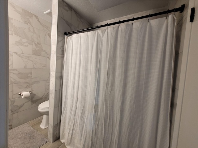 bathroom featuring toilet, curtained shower, tile walls, and a textured ceiling